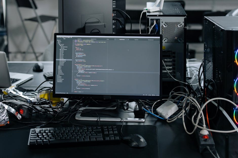 The image depicts a close-up view of a computer screen displaying lines of colorful programming code on a dark background. The code appears to be written in JavaScript, with syntax highlighting in gre